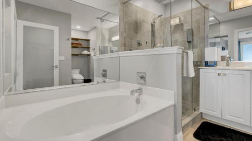 a white bathroom with a tub and a shower at Beachfront 3BDR Condo with Pool & Deck Ocean Views Ocean Blvd #102 by AvantStay in Isle of Palms