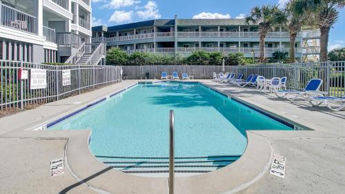 a swimming pool with blue chairs and a building at Beachfront 3BDR Condo with Pool & Deck Ocean Views Ocean Blvd #102 by AvantStay in Isle of Palms