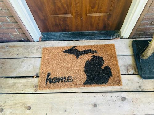 una alfombra de bienvenida frente a una puerta con la palabra hogar en Nickz Cozy Cabin, en Fenton