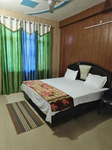 a bedroom with a large bed with green curtains at Radha Madhav in Vrindāvan
