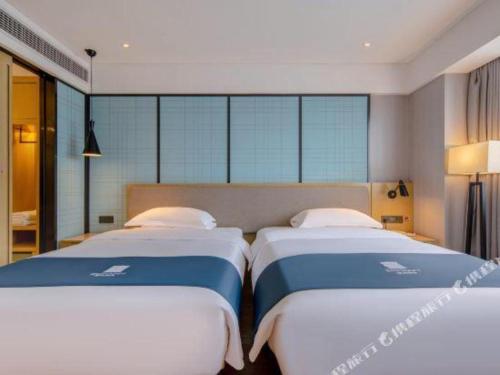 two twin beds in a room with windows at Echarm Hotel Nanning Chaoyang Square River View in Nanning