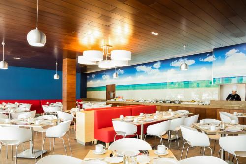 a restaurant with white tables and red chairs at Fiesta Inn Playa del Carmen in Playa del Carmen