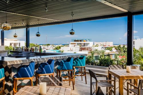 a bar on the roof of a building with blue chairs and tables at Fiesta Inn Playa del Carmen in Playa del Carmen