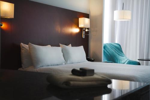 a hotel room with a bed and a blue chair at Fiesta Inn Playa del Carmen in Playa del Carmen