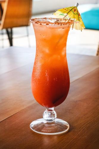 a drink in a glass on a table with an umbrella at Fiesta Inn Playa del Carmen in Playa del Carmen