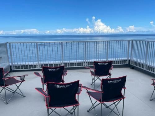 a group of chairs sitting on a balcony overlooking the ocean at AZホテル inn 奄美佐仁 Ocean View in Sani