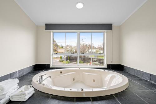 a large white tub in a room with a window at Cottage Mews Motel in Taupo