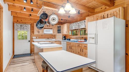a kitchen with wooden cabinets and a white refrigerator at Twin Creeks Lodge by AvantStay 33 Acre Retreat in Brevard