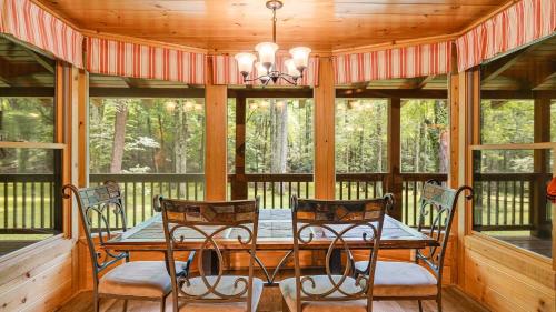a screened in porch with a wooden table and chairs at Twin Creeks Lodge by AvantStay 33 Acre Retreat in Brevard
