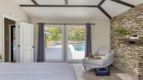 1 dormitorio con cama, silla y pared de piedra en Amber Refresh by AvantStay Pool and Hot Tub, en Jefferson City