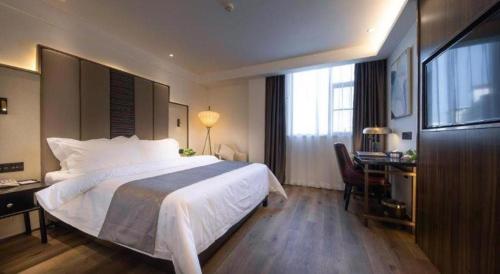 a hotel room with a large bed and a desk at Jinjiang Metropolo Haikou East High Speed Railway Station Normal University in Haikou