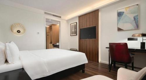 a bedroom with a white bed and a red chair at Jinjiang Metropolo Haikou East High Speed Railway Station Normal University in Haikou