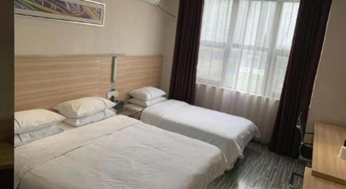 two beds in a hotel room with a window at City Comfort Inn Yichang Dongshan Three Gorges University Shuiyuecheng in Yichang