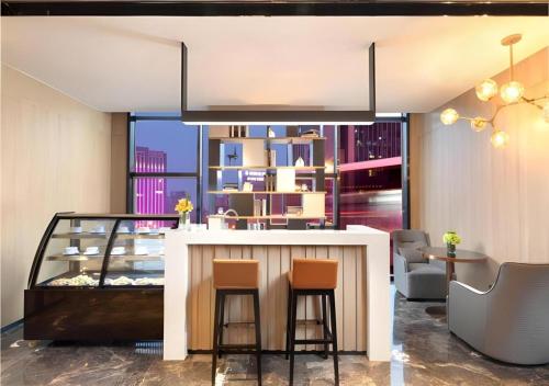 a lobby with a bar with chairs and a large window at Echarm Hotel Shenyang Zhongjie North Station Metro Station in Shenyang