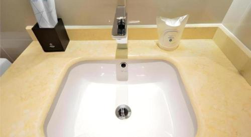 a white sink in a bathroom with a soap dispenser at City Comfort Inn Xiaogan Hubei Engineering College in Xiaogan