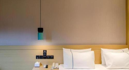 a bed with white pillows and a light above it at City Comfort Inn Xiaogan Hubei Engineering College in Xiaogan
