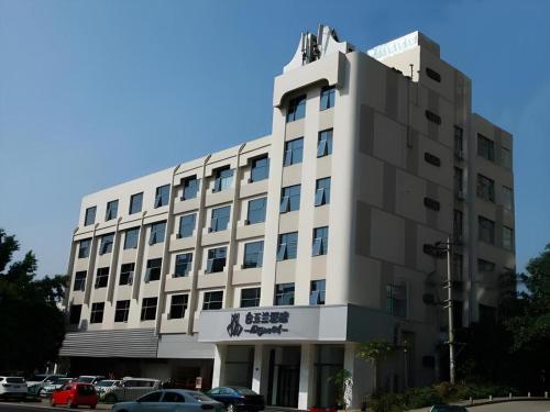 a large white building with cars parked in a parking lot at Magnotel Hotel Xiamen North Station Binhai in Xiamen