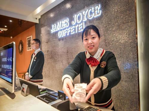 a woman holding a box of food in a store at James Joyce Coffetel Luoyang Longmen High-speed Railway Station Baolong Plaza in Luoyang