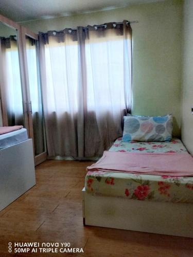a bedroom with a bed with pink sheets and curtains at Kara's Condotels in Cebu City