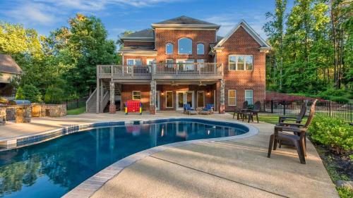a home with a swimming pool in front of a house at Lake Escape by AvantStay Lakefront Private Dock in Mooresville