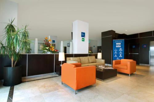 a lobby with two orange chairs and a couch at One Toluca Aeropuerto in Toluca