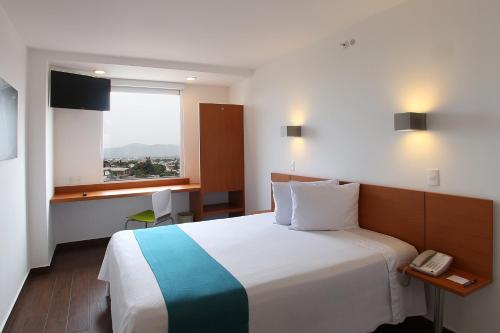 a hotel room with a large bed and a phone at One Cuernavaca in Cuernavaca