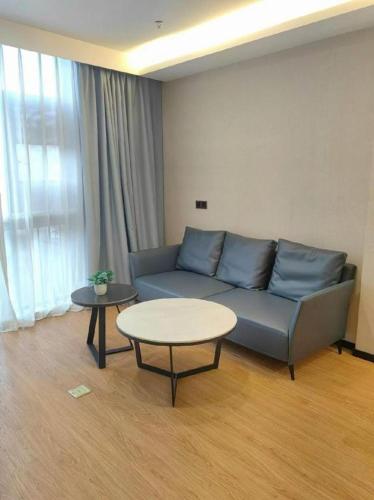 a living room with a blue couch and a table at GreenTree Inn Express Zhangjiagang Hexing Town Shazhou Professional Institue of Technology in Qiwei