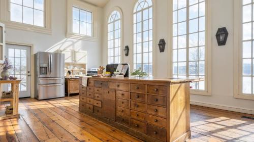 a kitchen with a wooden island in a room with windows at River House by AvantStay Historic Secluded Estate on the Hudson River w Pool Sleeps 24 in Hudson