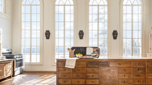 a kitchen with tall windows and a large wooden island at River House by AvantStay Historic Secluded Estate on the Hudson River w Pool Sleeps 24 in Hudson