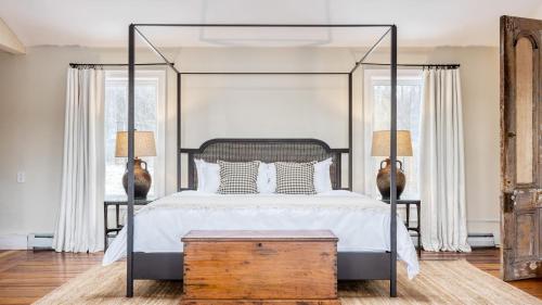 a bedroom with a large canopy bed with a wooden trunk at River House by AvantStay Historic Secluded Estate on the Hudson River w Pool Sleeps 24 in Hudson