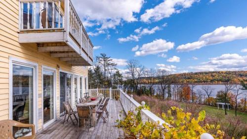 a deck with a table and chairs on a house at River House by AvantStay Historic Secluded Estate on the Hudson River w Pool Sleeps 24 in Hudson
