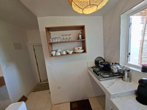 a white kitchen with a stove and a window at Essaouira Stay with private Terrace in Essaouira