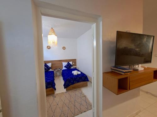 a living room with a television and blue pillows at Essaouira Stay with private Terrace in Essaouira
