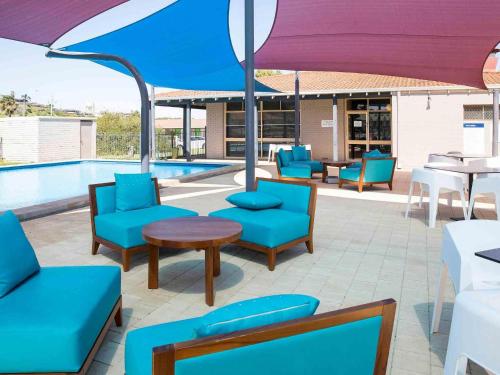 a patio with chairs and tables and an umbrella at ibis Styles Geraldton in Geraldton