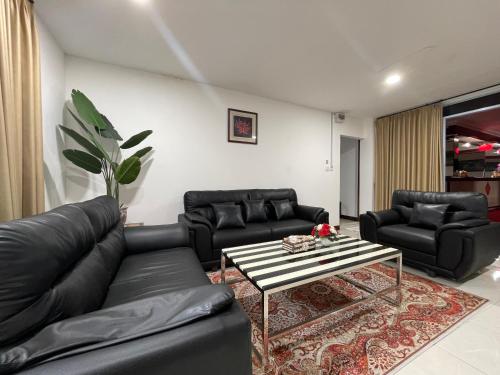 a living room with black leather couches and a coffee table at Hotel Riau Holidays in Tanjung Pinang 