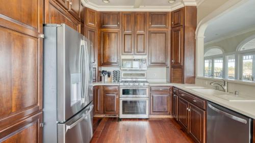a kitchen with wooden cabinets and a stainless steel refrigerator at Haven by AvantStay Luxury Beachfront Home w Pool Gorgeous Patios in Sullivans Island