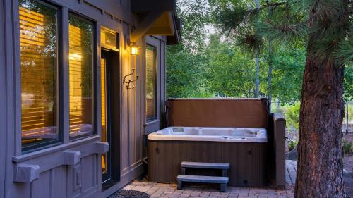 a bath tub on the side of a house with a tree at Klamath by AvantStay Premier Lakeside Cabin w Spa Fire Pit Lake Views in Bend
