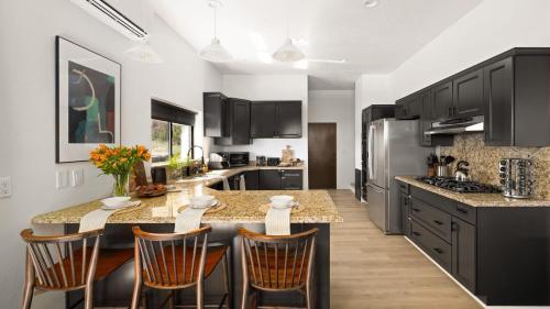 a kitchen with black cabinets and a kitchen island with chairs at Roca Roja by AvantStay Mountain Views in the Heart of Sedona in Sedona