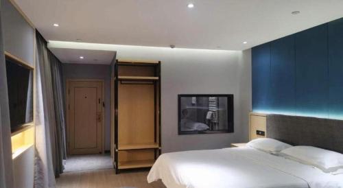 a bedroom with a large bed and a blue wall at Green Tree Inn Urumqi San'gong Metro Station Exit in Ürümqi