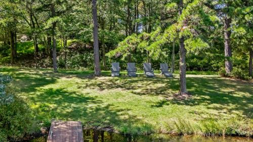 a park with chairs on the grass near a pond at Lake It Right by AvantStay Lakefront w Dock Hot Tub Fire Pit Game Room in Long Pond