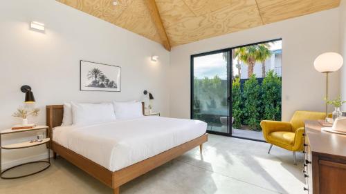 a bedroom with a large bed and a yellow chair at Blackhaus B : 4 Bedroom Suite by AvantStay 4-Rooms in Palm Springs