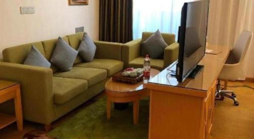 a living room with a couch and a television at Vienna Hotel Guangdong Zhaoqing Sihui Tianguangxu in Zhaoqing