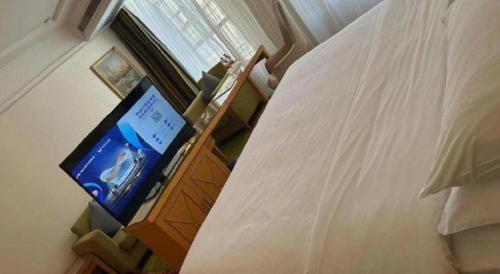 a bedroom with a bed and a television on a dresser at Vienna Hotel Guangdong Zhaoqing Sihui Tianguangxu in Zhaoqing