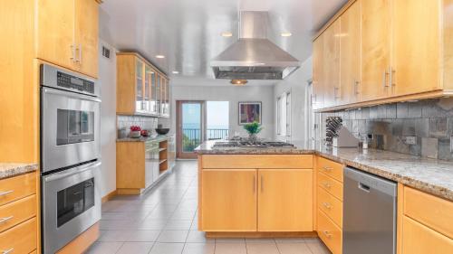 a large kitchen with wooden cabinets and stainless steel appliances at Dume Point by AvantStay Tennis Pool in Malibu in Malibu