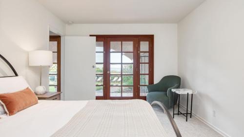 a bedroom with a bed and a green chair at Dume Point by AvantStay Tennis Pool in Malibu in Malibu