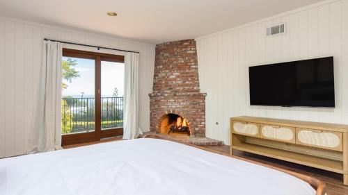 a bedroom with a fireplace and a television and a bed at Dume Point by AvantStay Tennis Pool in Malibu in Malibu