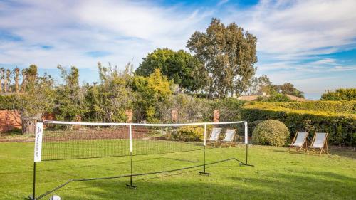 a tennis court with two chairs and a net at Dume Point by AvantStay Tennis Pool in Malibu in Malibu