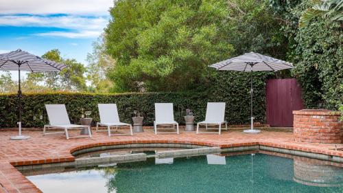a patio with chairs and umbrellas next to a pool at Dume Point by AvantStay Tennis Pool in Malibu in Malibu