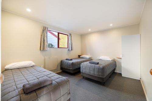 a bedroom with two beds and a chair and a window at Kaikōura TOP 10 Holiday Park in Kaikoura