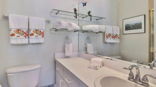 Un baño con lavabo, inodoro y espejo. en Breezy Bungalow by AvantStay Close 2 Zachary Taylor State Park Beach w Shared Pool Week Long Stays, en Key West